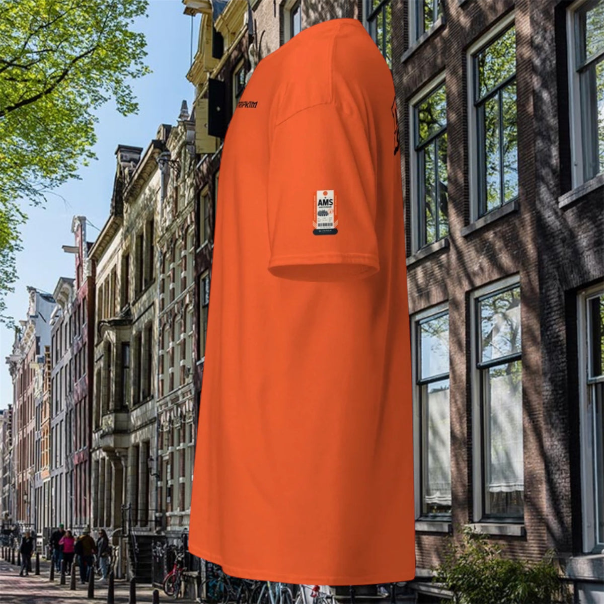 T-shirt Amsterdam AMS orange, vue de profil devant des maisons d'Amsterdam - TRIPKIM