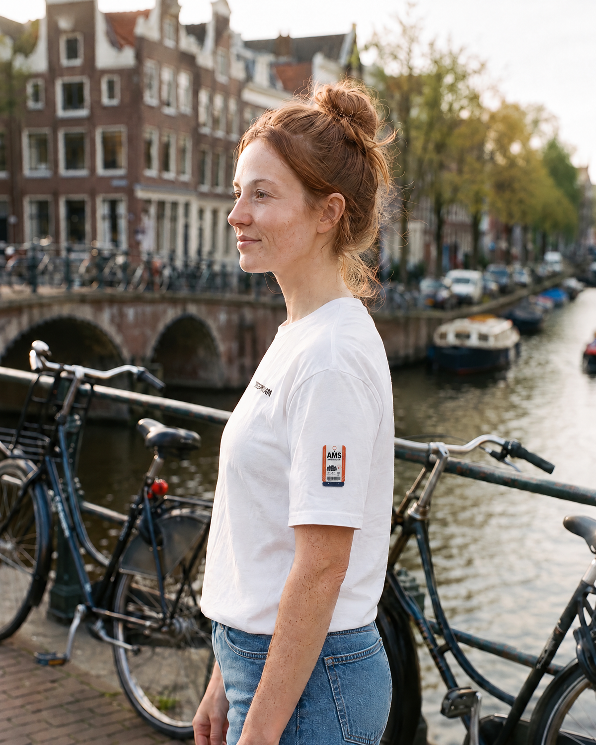 T-shirt Amsterdam AMS blanc porté de profil, étiquette bagage AMS sur la manche - TRIPKIM
